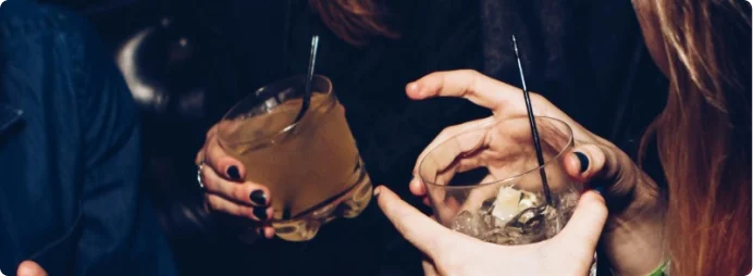 Two women converse with each other, holding drinks in their hands.